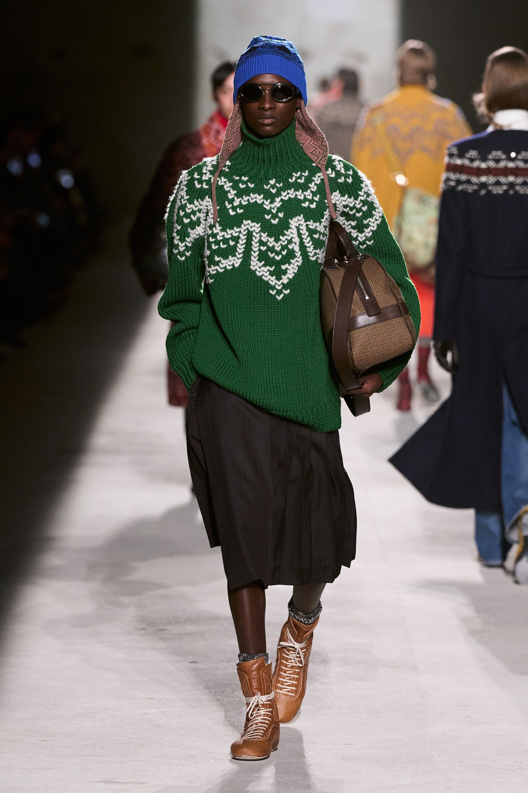 Dries Van Noten 2026秋冬以高度成熟的综合色彩与织物语言，继续书写其标志性的“文化层叠美学”。民族图案针织、拼接围巾、军装轮廓与优雅大衣在行走中形成复杂而克制的视觉节奏，色彩看似丰富却始终维持理性秩序。这是一种属于思想型穿着者的浪漫，不依赖情绪爆发，而通过织物、比例与色块的精密组合，构建出安静却极具深度的男性诗意-顽石频道趋势研究